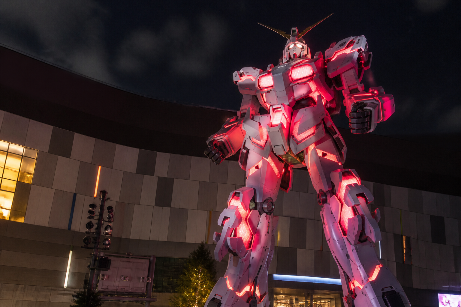 夜間のライトアップによって赤く発光しデストロイモードへと変形したガンダム立像